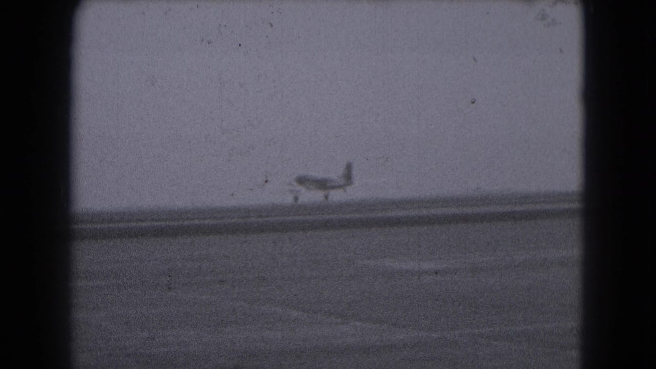 Small propeller airplane on a distant runway under a pale sky.