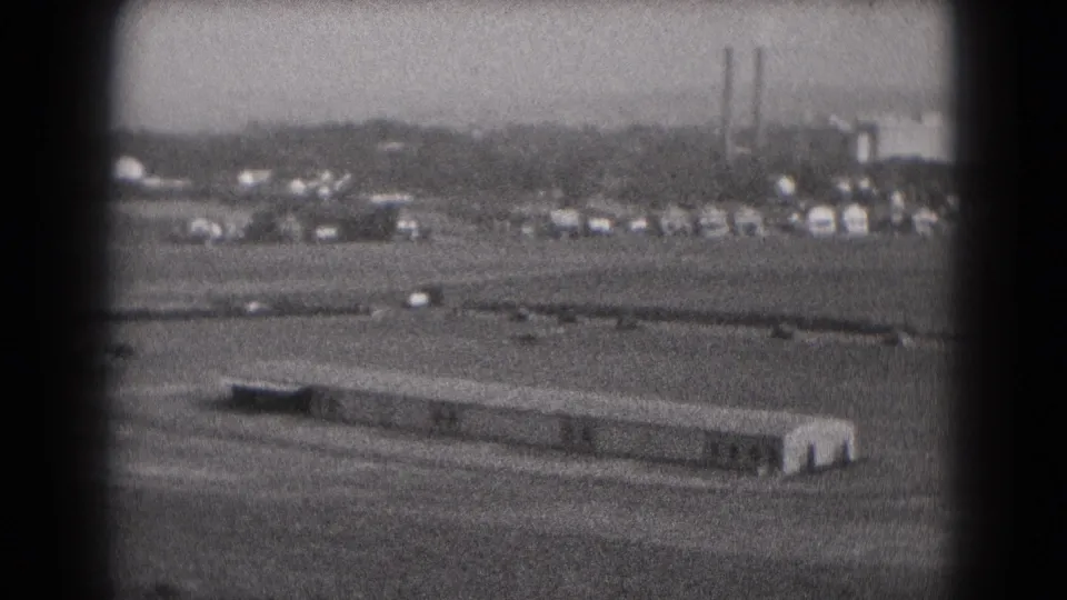 1975 Middletown, Pennsylvania frame with a long rectangular foreground building and slow road traffic near distant industrial buildings.