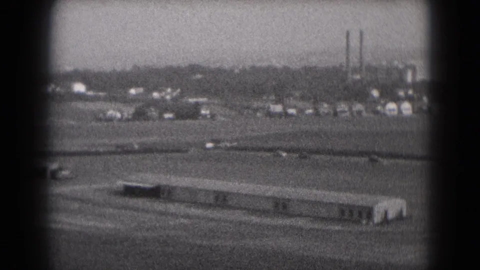 Small aircraft visible during an approach over Middletown, Pennsylvania airport grounds, with low buildings and stacks in the distance.