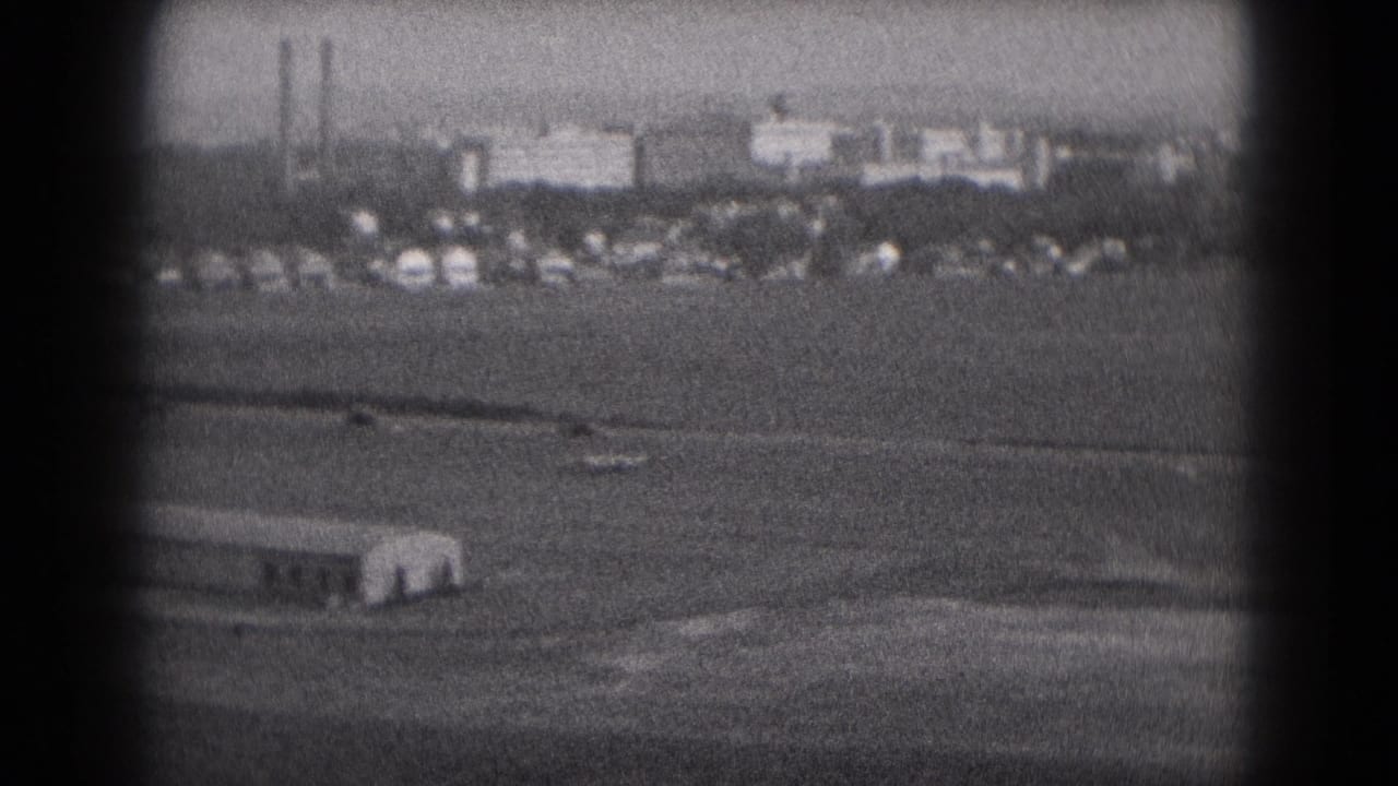 1975 Middletown, Pennsylvania 8mm view of distant buildings, stacks, and open ground seen through a dark vignetted frame.