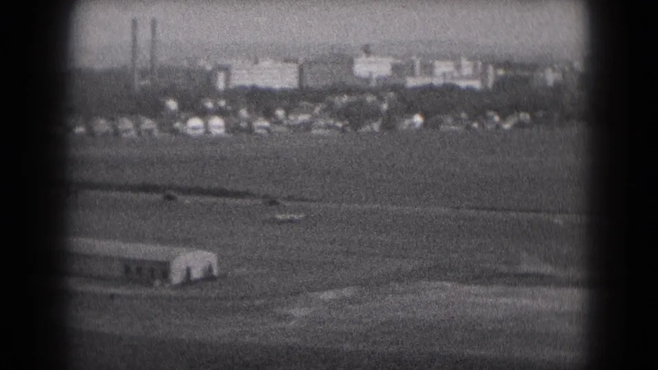 1975 Middletown, Pennsylvania 8mm view of distant buildings, stacks, and open ground seen through a dark vignetted frame.