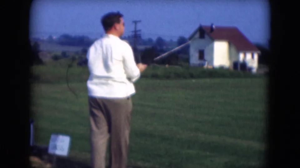 Seen from behind, the man raises a golf club during a practice swing on grass in Middletown, Pennsylvania, 1975.