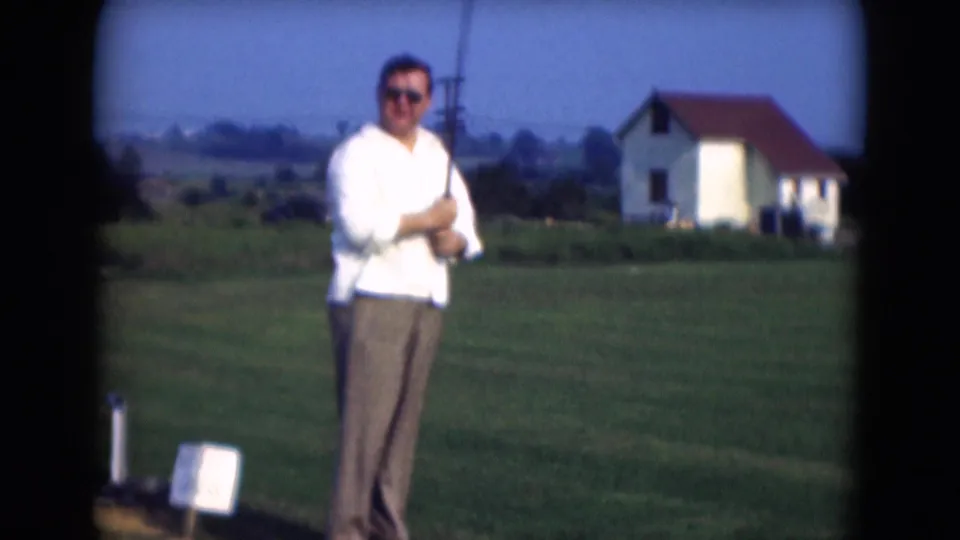 A man wearing sunglasses holds a golf club and faces the camera on a grassy field in 1975 Middletown, Pennsylvania.