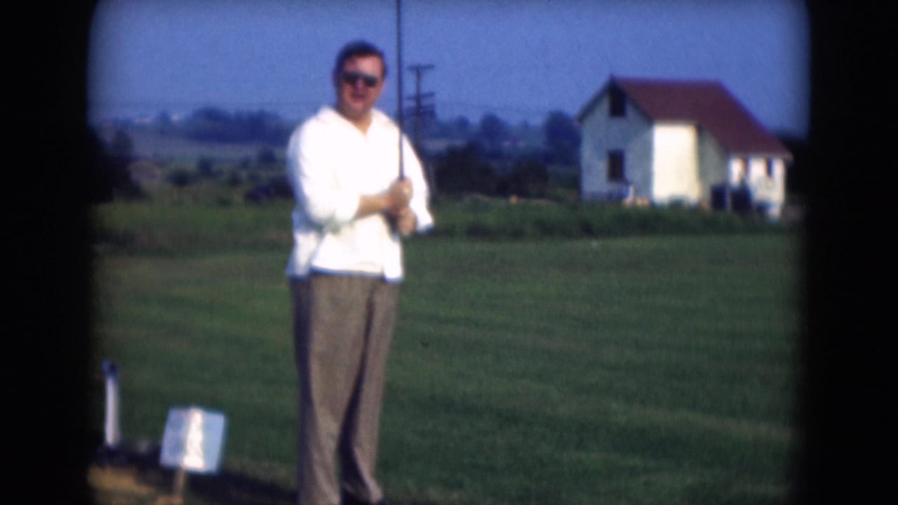 In Middletown, Pennsylvania in 1975, a man in a white shirt and brown trousers stands with a golf club on a grassy field.