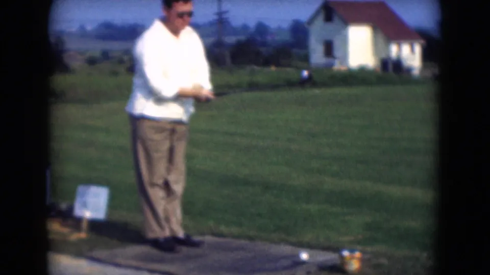 The golfer shifts into his swing in the 1975 Middletown home movie, standing near a visible ball on the tee area.
