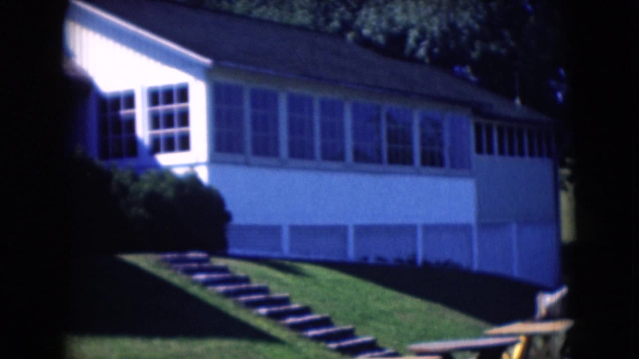 White house with large windows, exterior steps, lawn, and a picnic table.