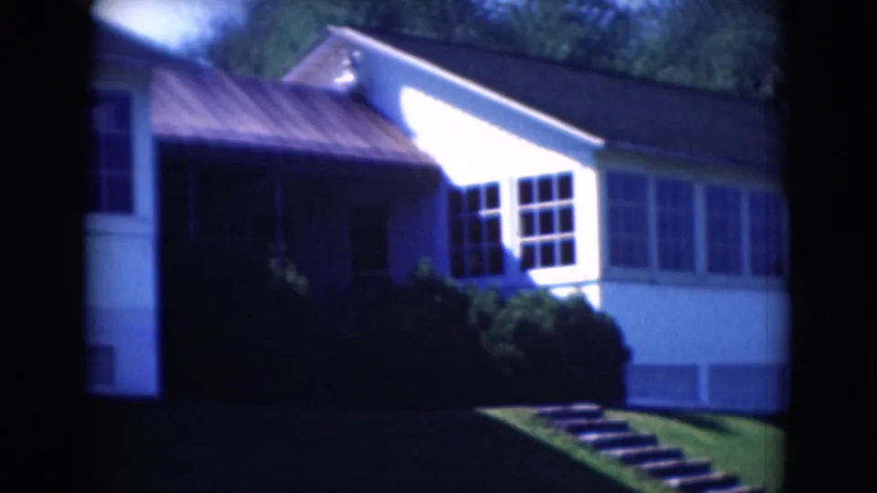 1975 Middletown, Pennsylvania home-movie frame with a closer view of the white house, window wall, shrubs, lawn, and steps.