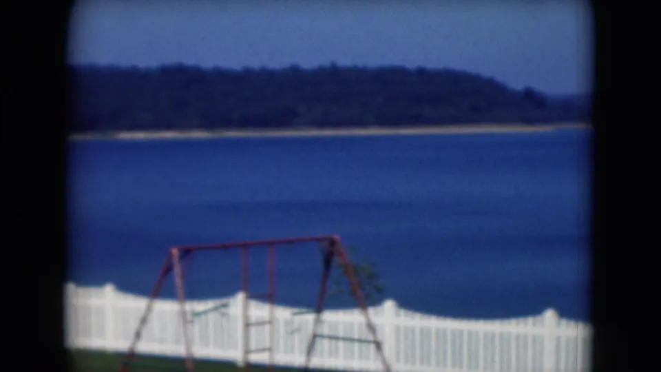 1975 Middletown, Pennsylvania frame showing a red swing set, white fence, blue lake, and wooded hills across the water.