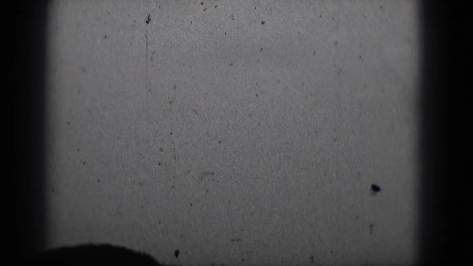 1975 Middletown 8mm frame showing a blank projection screen and seated audience silhouettes in a dark theater setting.