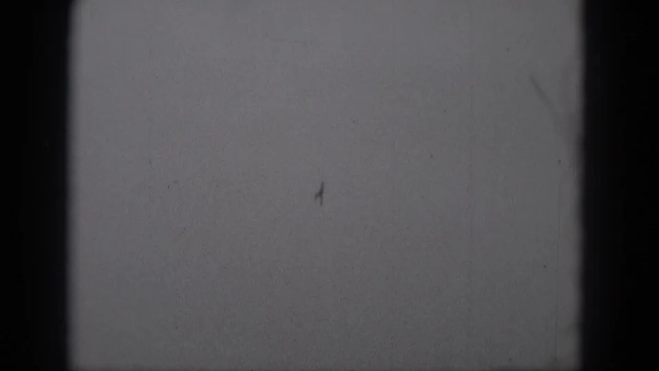 Near the end of the 1975 Middletown 8mm clip, a tiny aircraft silhouette is visible against a soft, grainy sky.