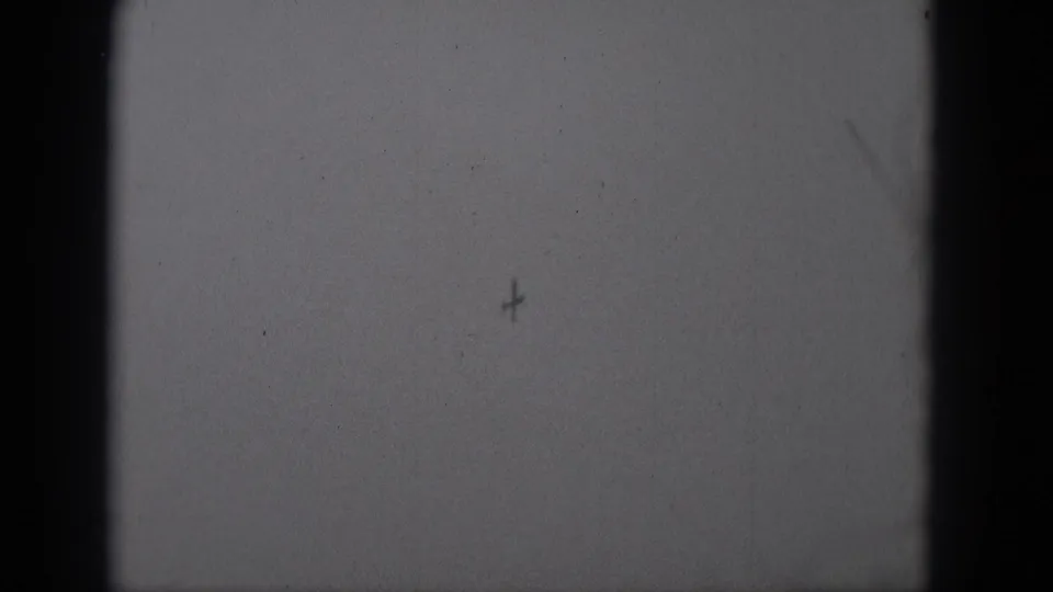 Black-and-white 8mm frame from Middletown metadata showing a distant aircraft shape near the upper right sky area.
