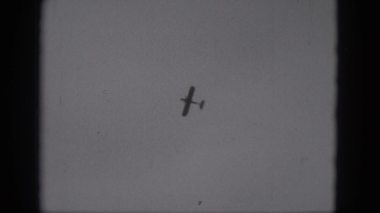 The aircraft remains small and dark against a plain sky in this 1975 Middletown, Pennsylvania home-movie frame.