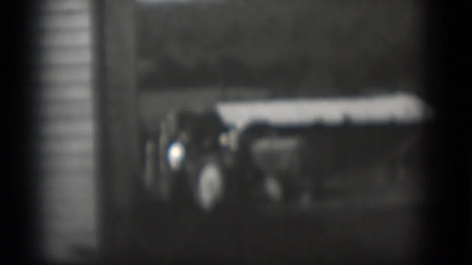 Middletown, Pennsylvania home-movie frame with a tractor or farm machine near a white building and indistinct people at the left.