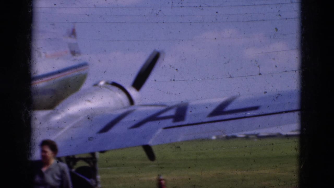 Propeller airplane wing with IAL lettering and a person partly visible near the aircraft.
