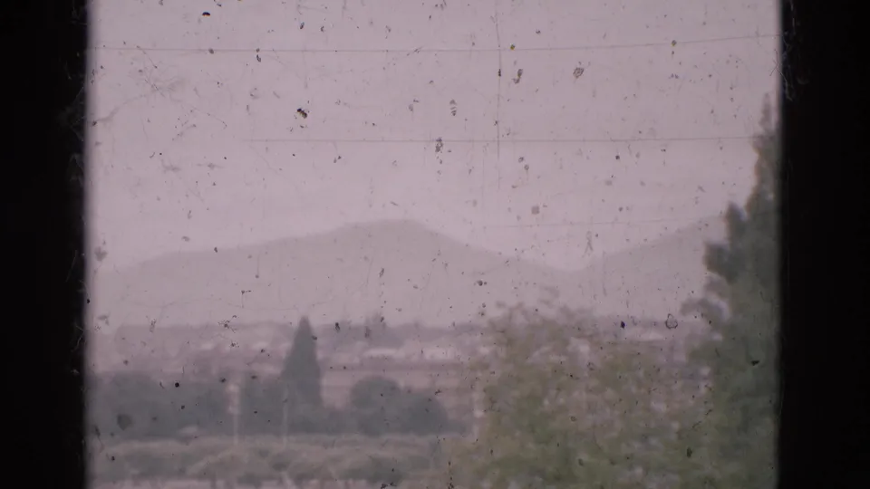 A soft 1975 Portugal landscape is partly obscured by a dark window mullion and marked film surface.