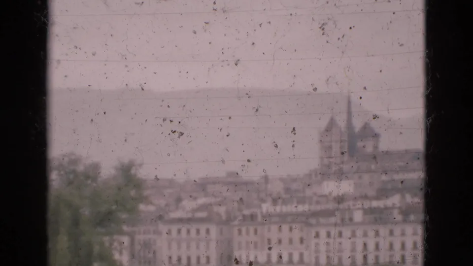 1975 Portugal town view with rooftops, a church-like spire, distant hills, and weathered 8mm film texture.
