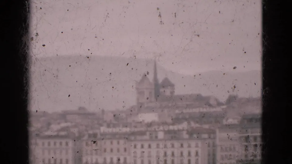 1975 Portugal 8mm frame showing a soft-focus city skyline across water through dusty window glass, with twin spires in the distance.