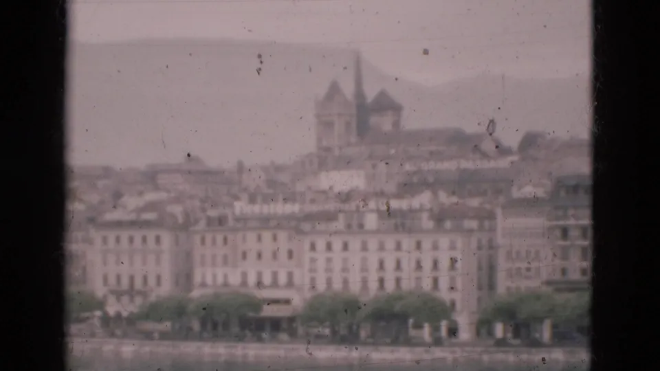 1975 8mm Portugal travel footage looking through dark window edges toward a soft, hazy waterfront cityscape.