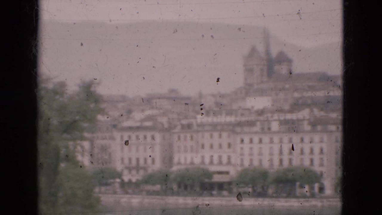 A hazy Portugal waterfront city view in 1975, framed by a window with buildings and a tower across the water.