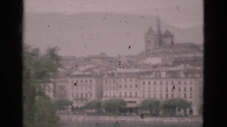 A hazy Portugal waterfront city view in 1975, framed by a window with buildings and a tower across the water.