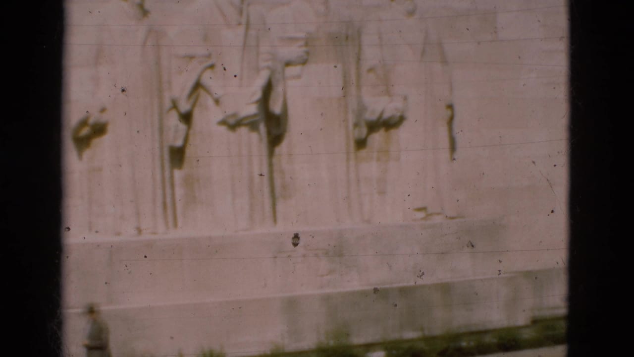 Stone relief wall with a small distant figure near the base.