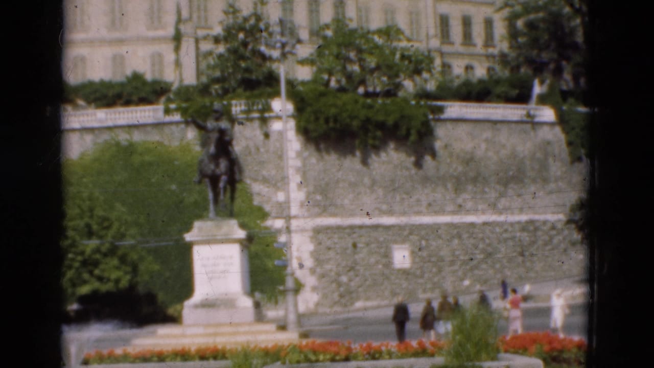 Equestrian statue and terrace with several people walking along the lower path.