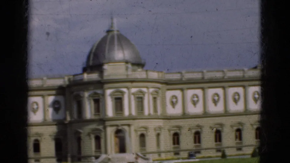 1975 Portugal home-movie frame showing the domed section and long ornate facade of a public landmark building.