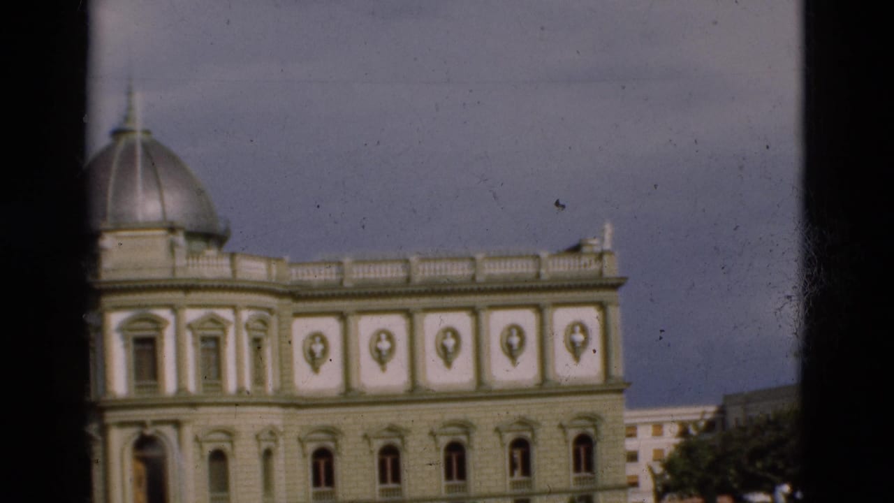 1975 Portugal home-movie frame of a grey and white domed building with arched windows, viewed through a dark interior or vehicle frame.