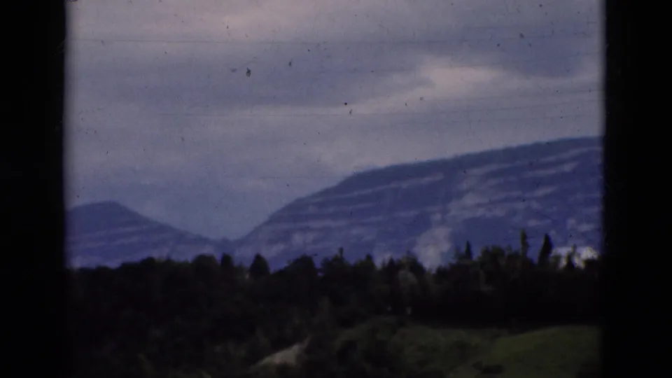 Portuguese mountain range and forested foreground on 8mm film, with dark vertical framing at the left and right edges.
