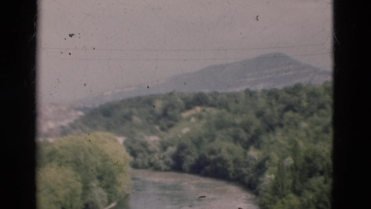 River valley and wooded hillside seen through a central dark window divider.