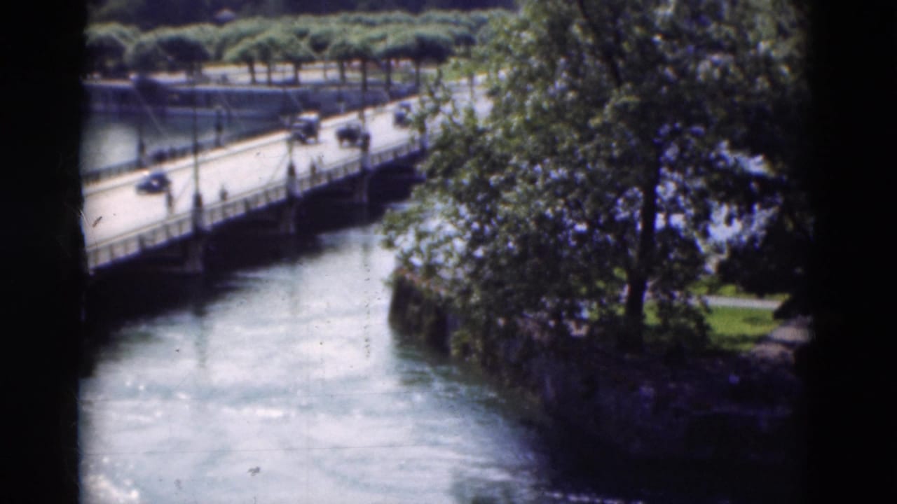 Low bridge over a river with cars crossing and trees along the bank.