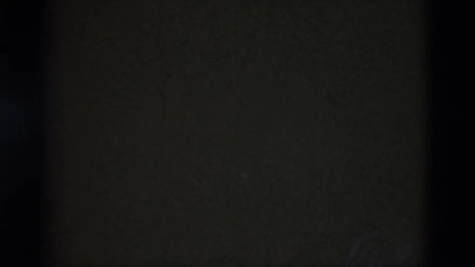 Mostly dark 8mm frame at the end of the clip, with faint film texture and minimal visible landscape detail.
