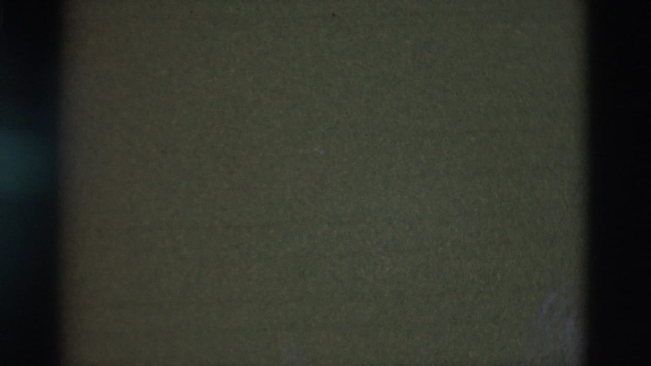 Mostly obscured 8mm frame from a Portugal 1975 home movie, showing only dark film texture and vertical shadow bands.