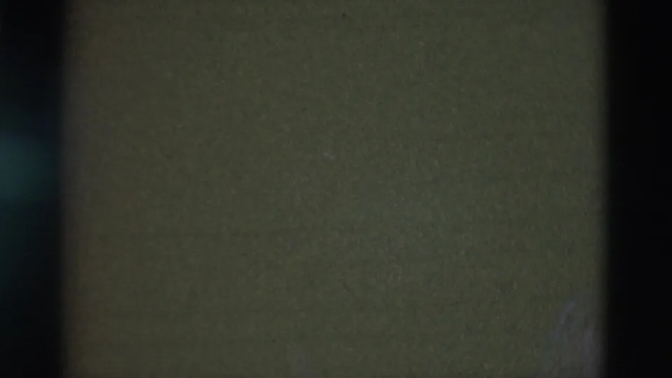 Mostly obscured 8mm frame from a Portugal 1975 home movie, showing only dark film texture and vertical shadow bands.