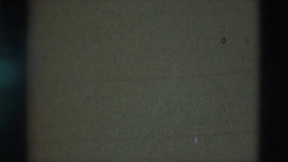 Mostly unreadable 8mm frame, likely from the 1975 Portugal clip, with green-brown density, grain, and small film marks.