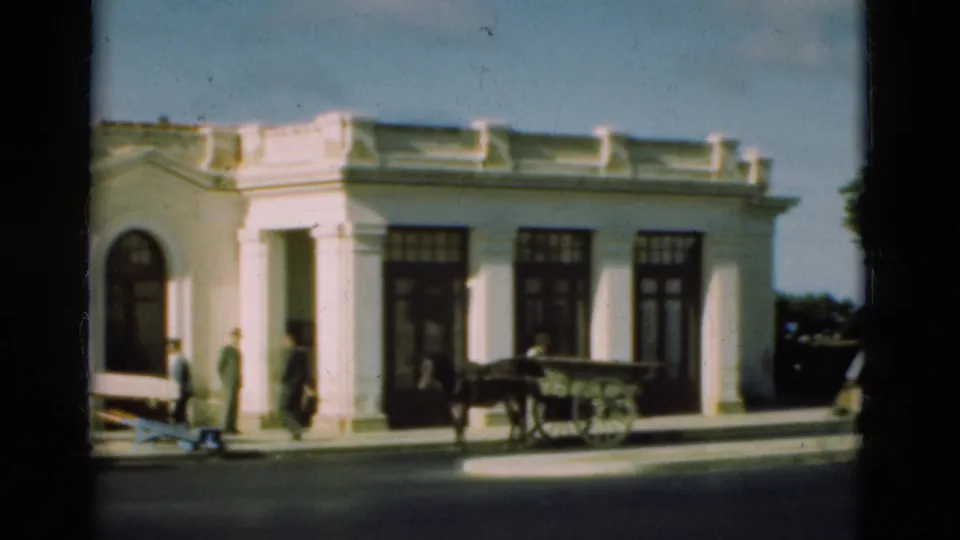 The 1975 Portugal street scene shows people outside a white building, with a horse-drawn cart near dark doorways and windows.