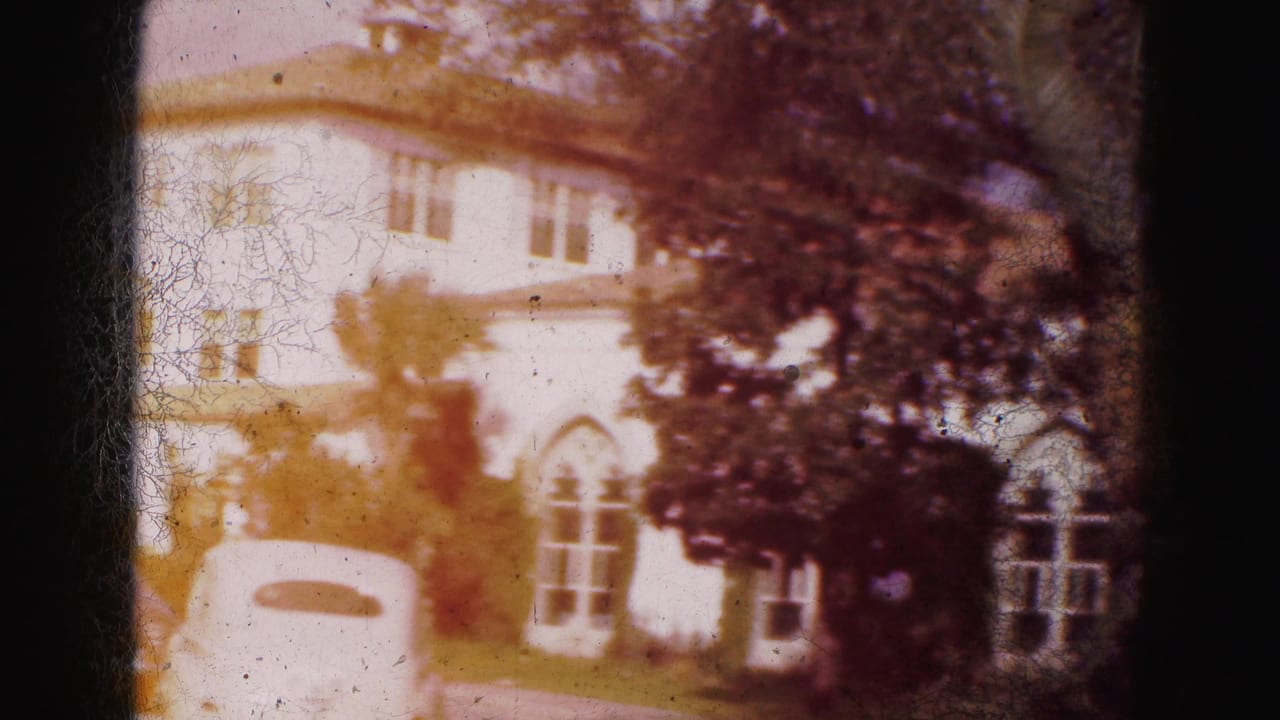 1975 8mm Florida home-movie frame showing a large white house with arched windows, trees, and a sunlit lawn.