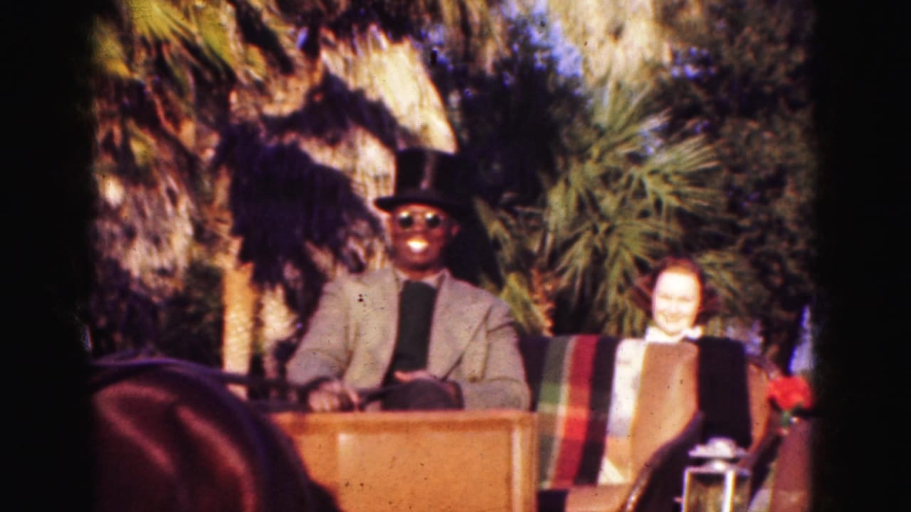 Close 1975 Florida carriage view with a top-hatted driver, smiling woman passenger, lantern, red flowers, and palms behind them.