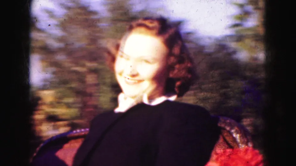 Soft 8mm close-up from the 1975 Florida carriage ride, showing a smiling woman passenger against motion-blurred greenery.