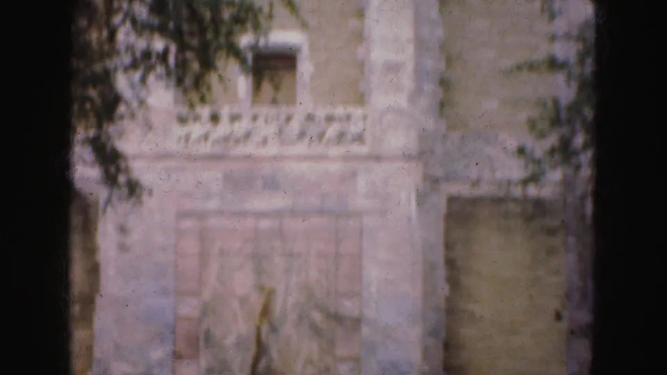 1975 8mm frame showing the lower portion of a stone monument in Florida Everglades travel footage, with carved details and heavy gate shadow.