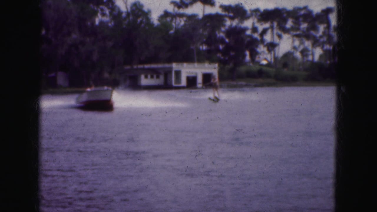 Motorboat and water-skier on a lake near a white shoreline building.