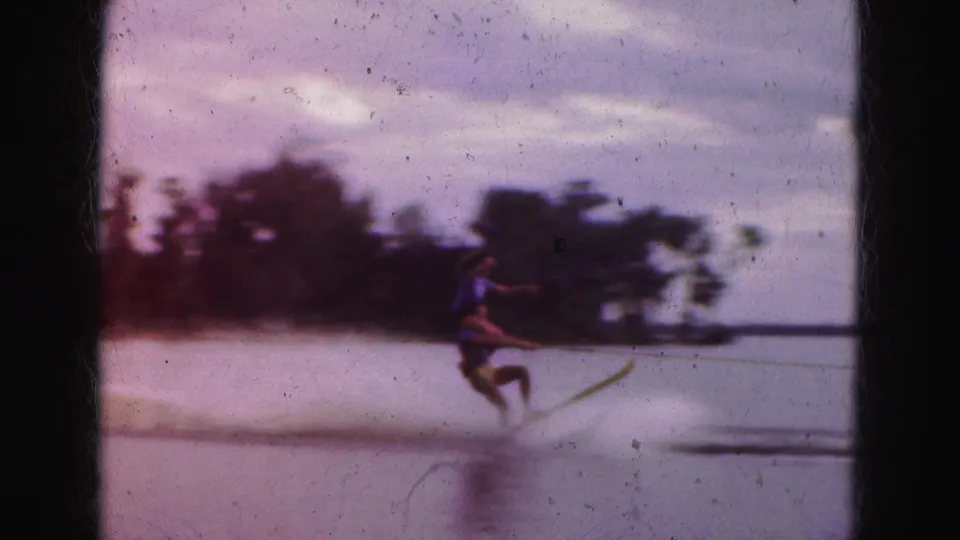 Soft 8mm frame from the 1975 Florida Everglades trip showing the skier leaning into motion on calm water.