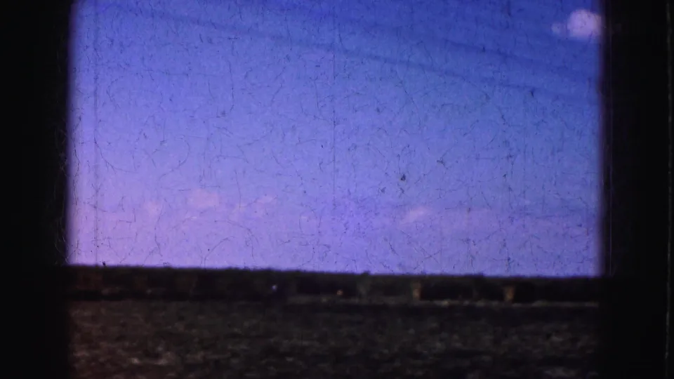 Soft 8mm closing frame with purple-blue sky, low dark foreground, and visible film wear from the 1975 Florida Everglades clip.