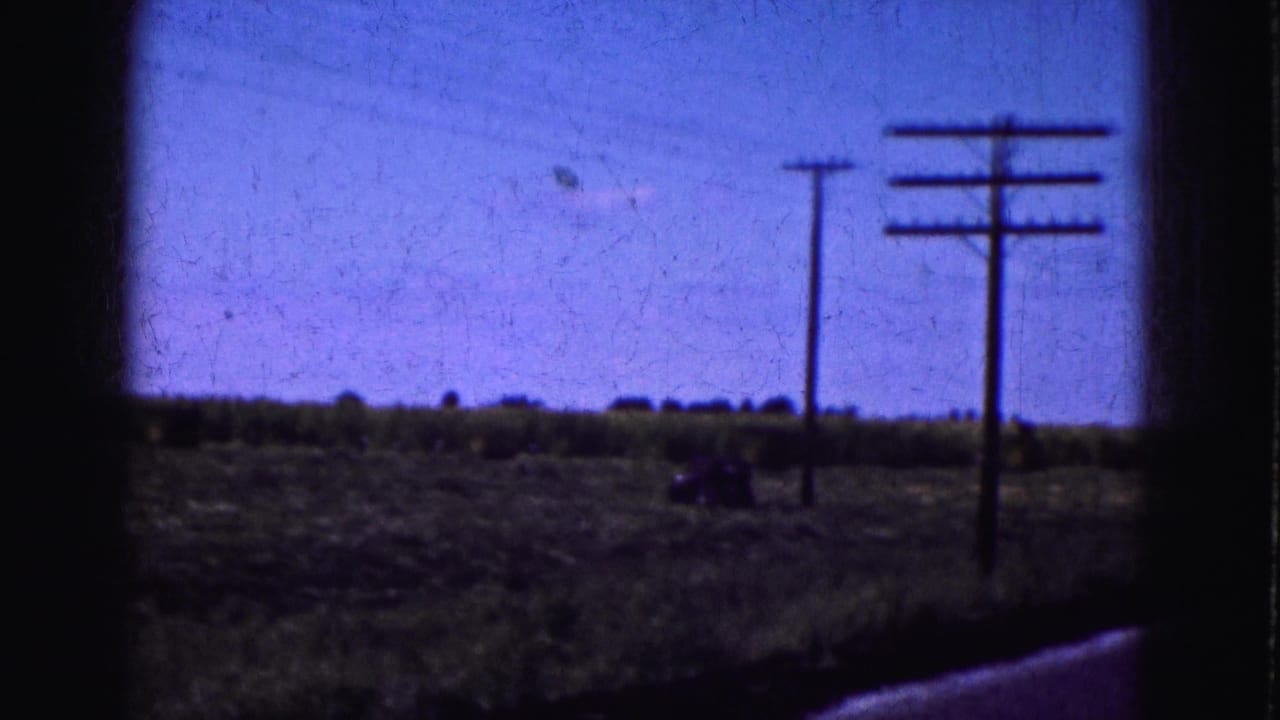 1975 8mm Florida Everglades travel view showing utility poles along an open rural roadside beneath a blue-shifted sky.