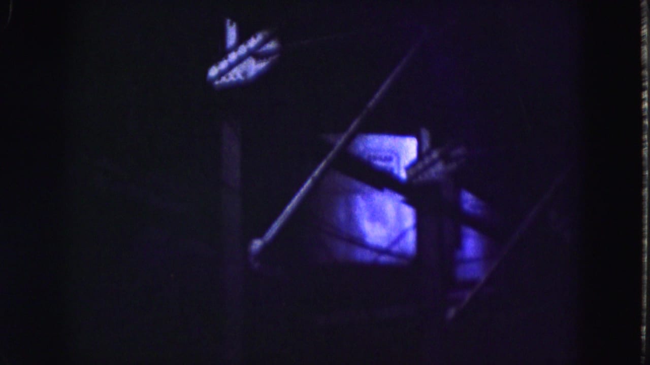 Underexposed interior view showing diagonal metal elements, a bright window, and purple-blue film color shift.