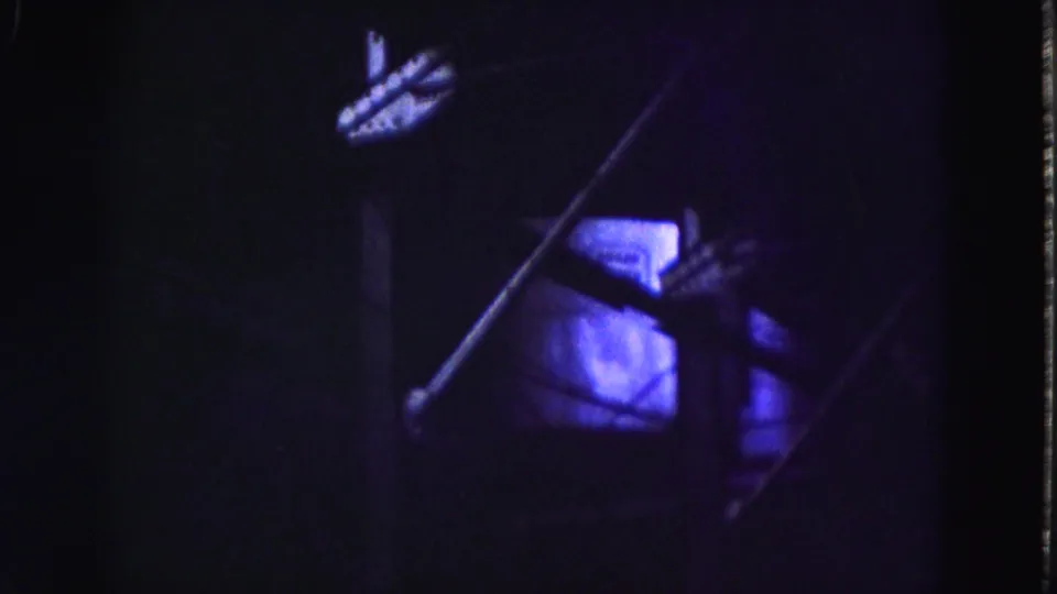 Underexposed interior view showing diagonal metal elements, a bright window, and purple-blue film color shift.