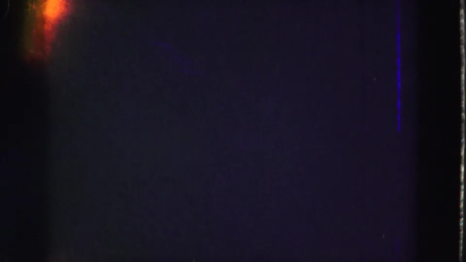 Underexposed 8mm frame from the 1975 Florida Everglades clip, showing gate edges and a small orange light leak.