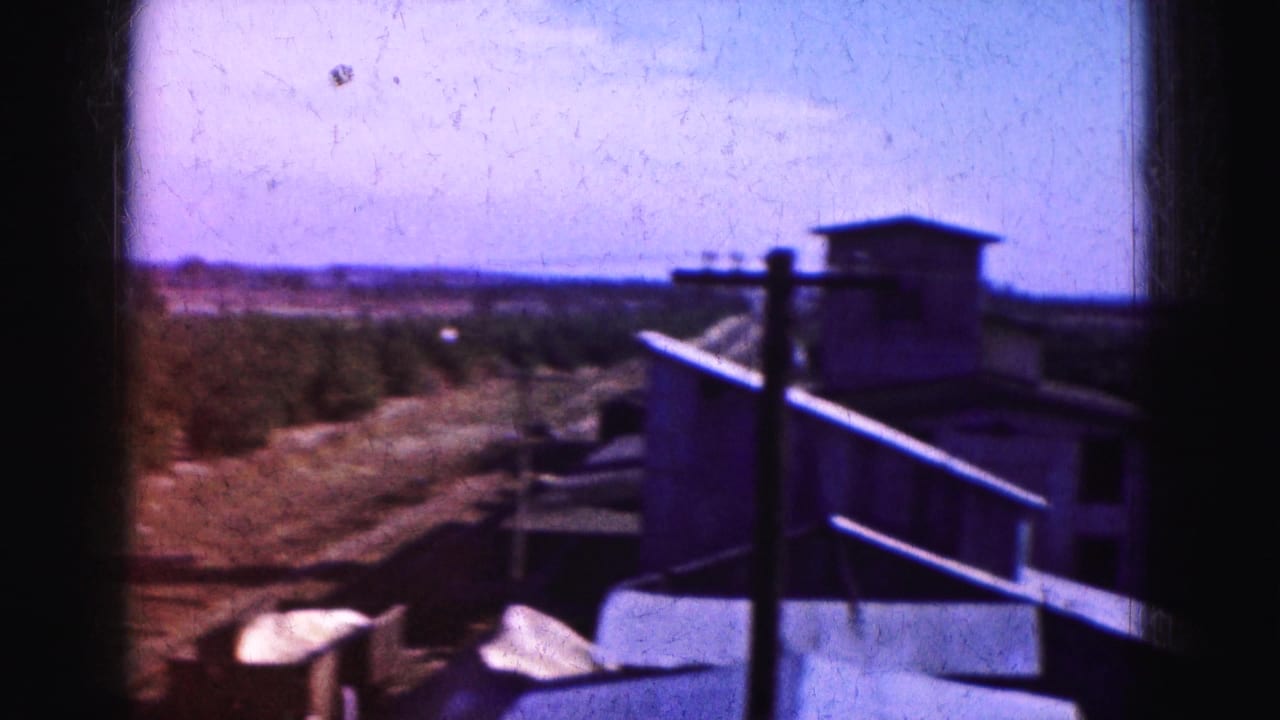 Roadside structure and railings beside open vegetation and a distant horizon.