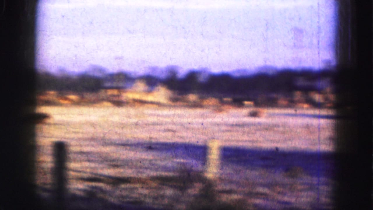 Soft distant view across water with posts and a low shoreline.