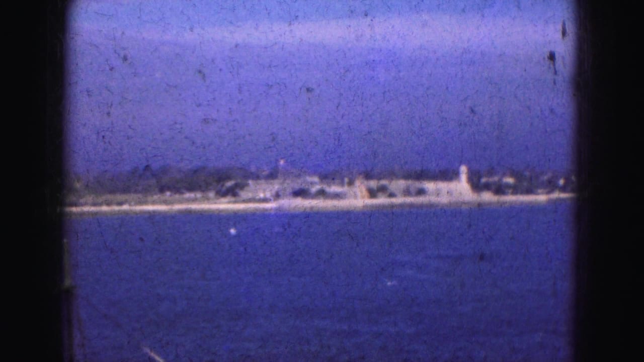 Wide blue water with a distant shoreline, small buildings, and a pale tower-like structure.
